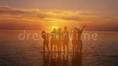 一大群朋友站在日落海滩上。 周末野餐概念